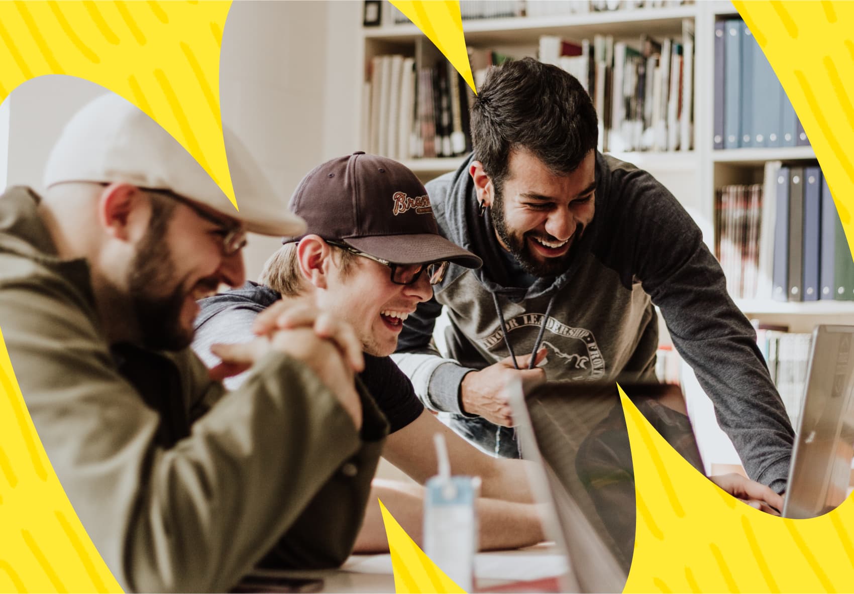 Three men laughing in front of a laptop