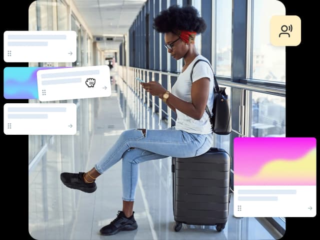 Woman sitting on suitcase in airport hallway, using a travel app.
