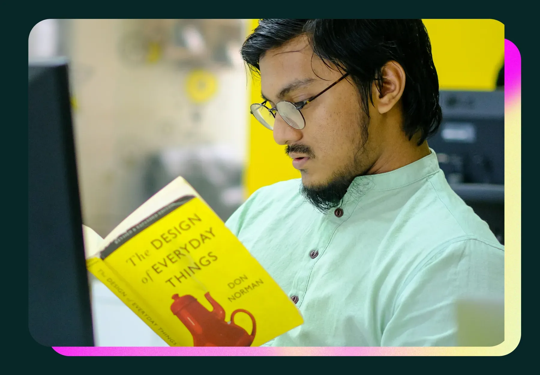 A man sitting down at his desk reading The Design of Everyday Things by Don Norman